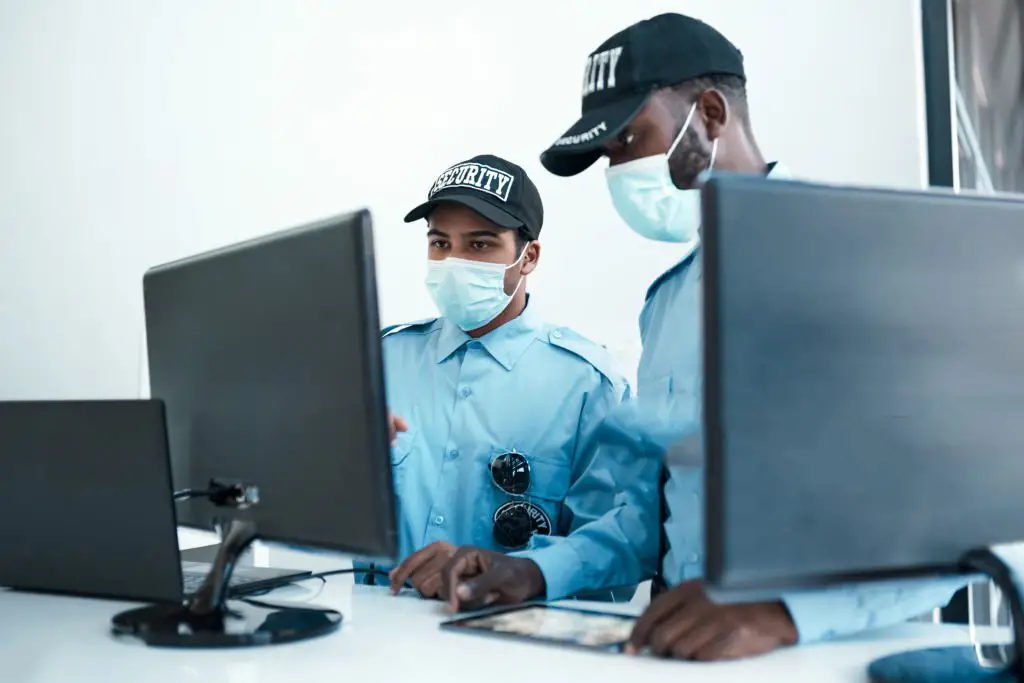 Deux jeunes agents de sécurité masqués en poste à l'accueil d'un bureau