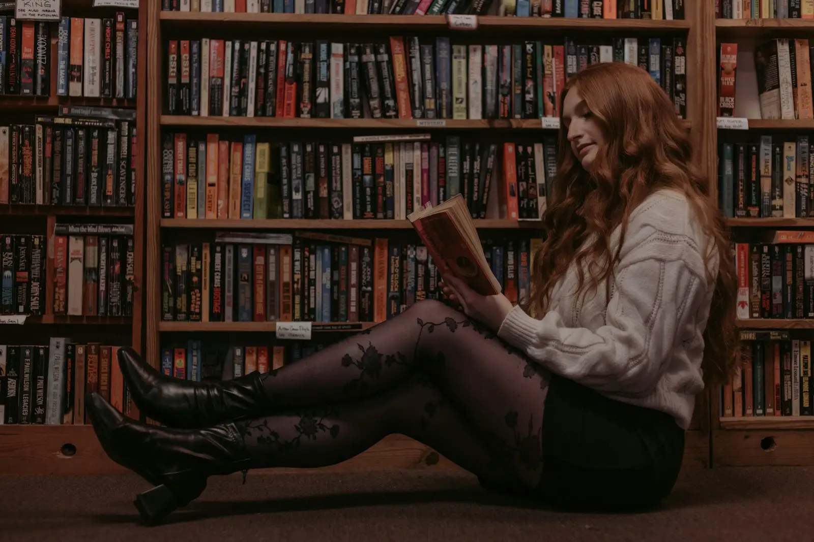une femme assise par terre en train de lire un livre